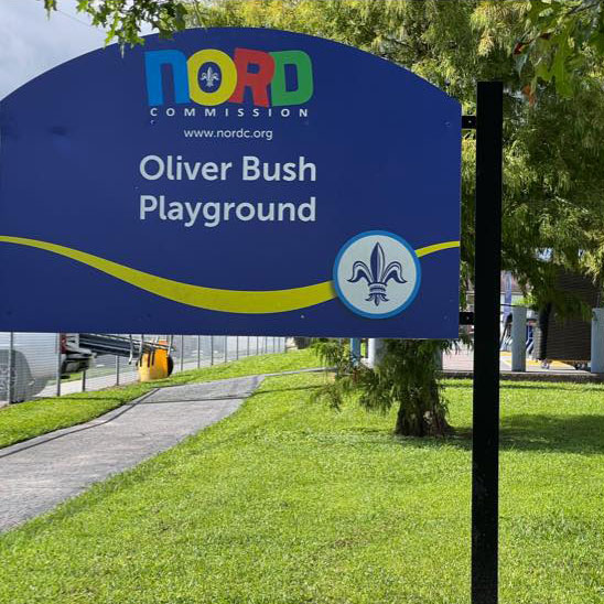 sign in the park with text: NORD Commission Oliver Bush Playground